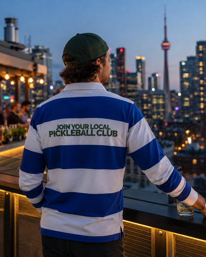 Man wearing pickleball polo on Toronto rooftop bar at dusk with city skyline