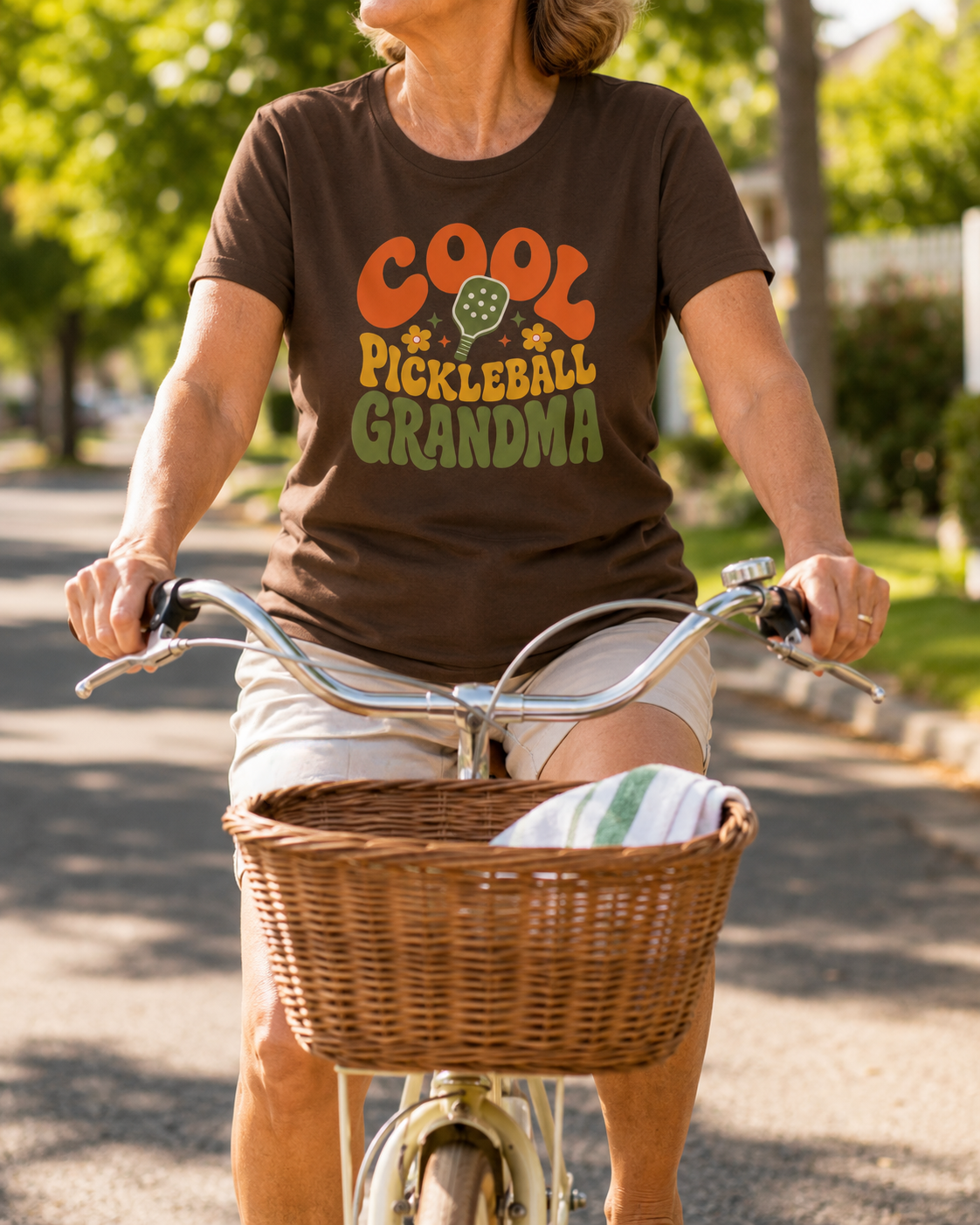 Woman wearing Cool Pickleball Grandma shirt riding a bicycle in neighborhood